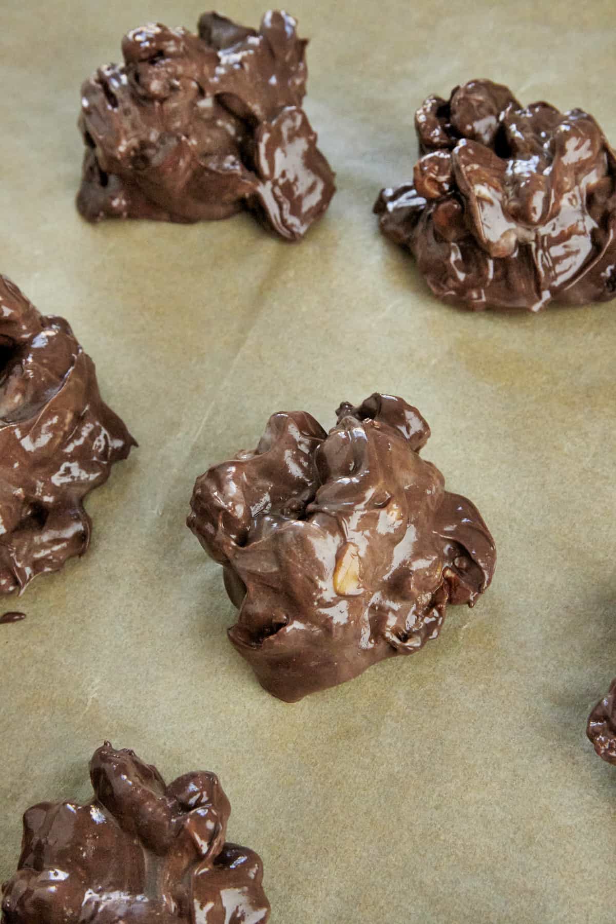 Hot caramel pecan clusters on a parchment lined baking sheet. 