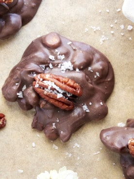 A chocolate caramel pecan cluster topped with a pecan and salt.