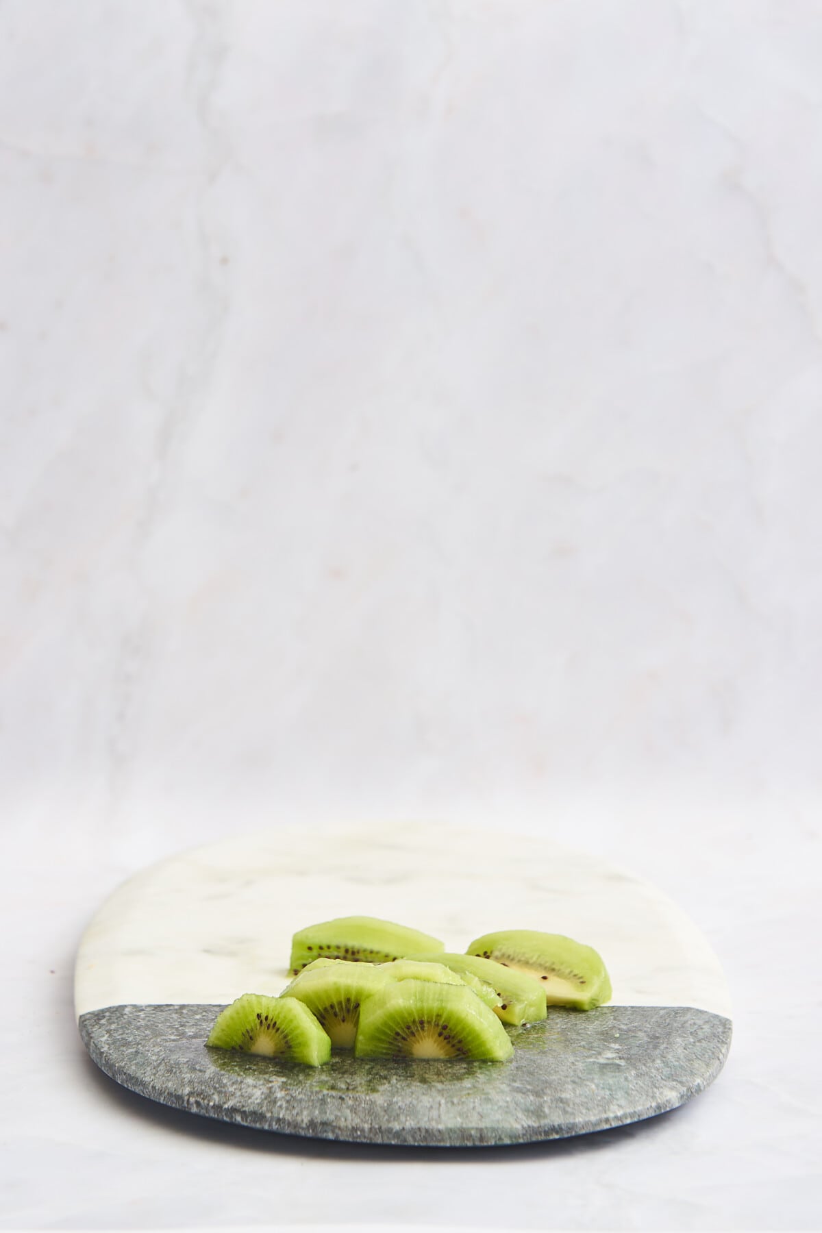 Skinless kiwi chunks on a marble cutting board. 