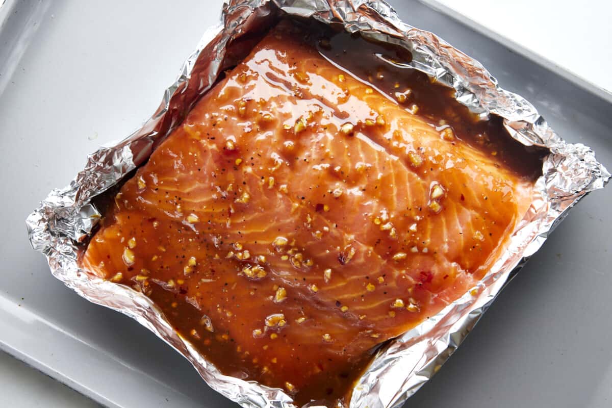 A salmon filet topped with a honey garlic glaze in a foil packet. 