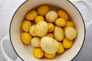 Peeled white and yellow potatoes in a pot.