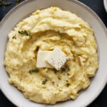 A bowl of the best mashed potatoes recipe topped with pads of butter.