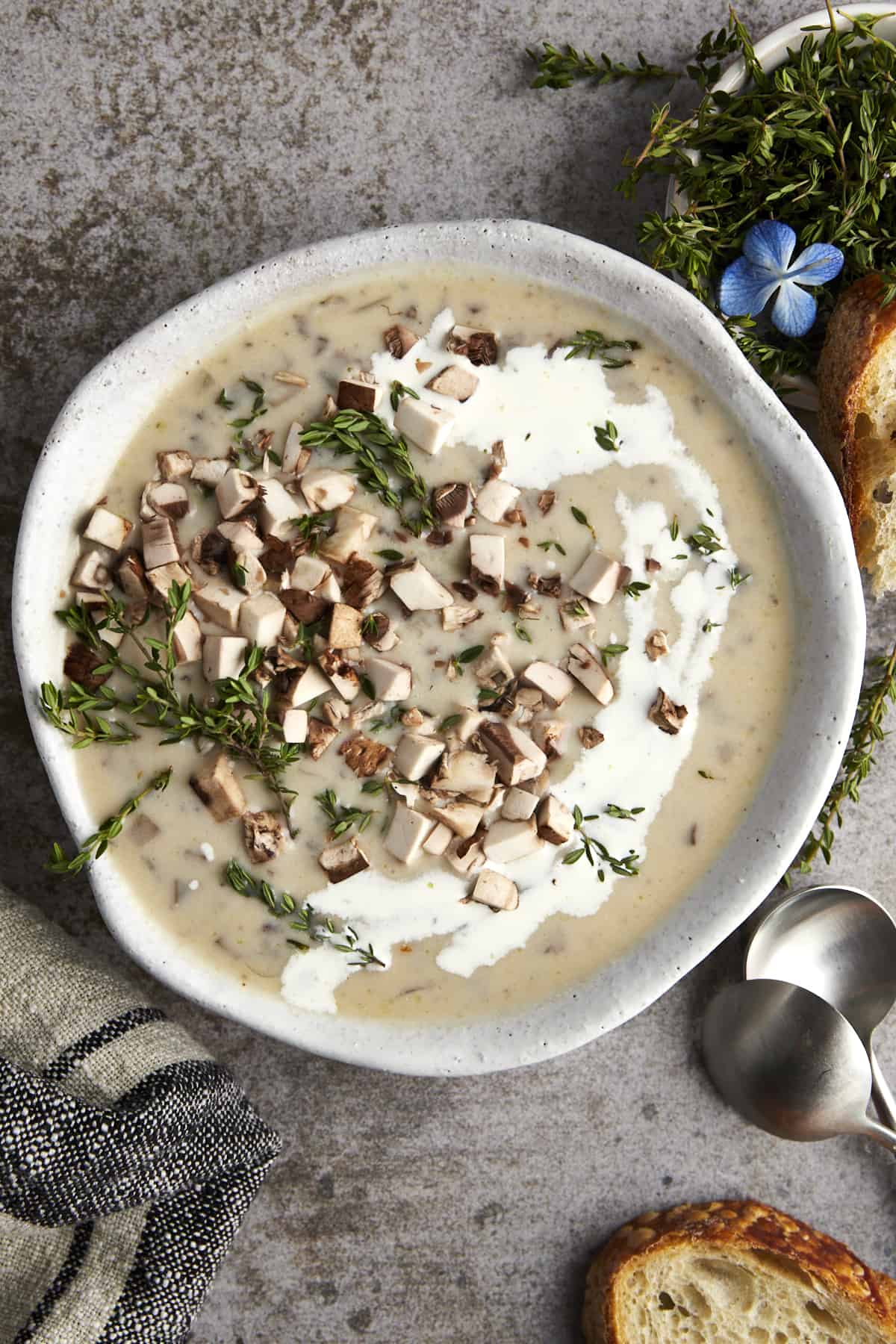 A bowl of creamy mushroom soup with thyme and chopped mushrooms on top. 