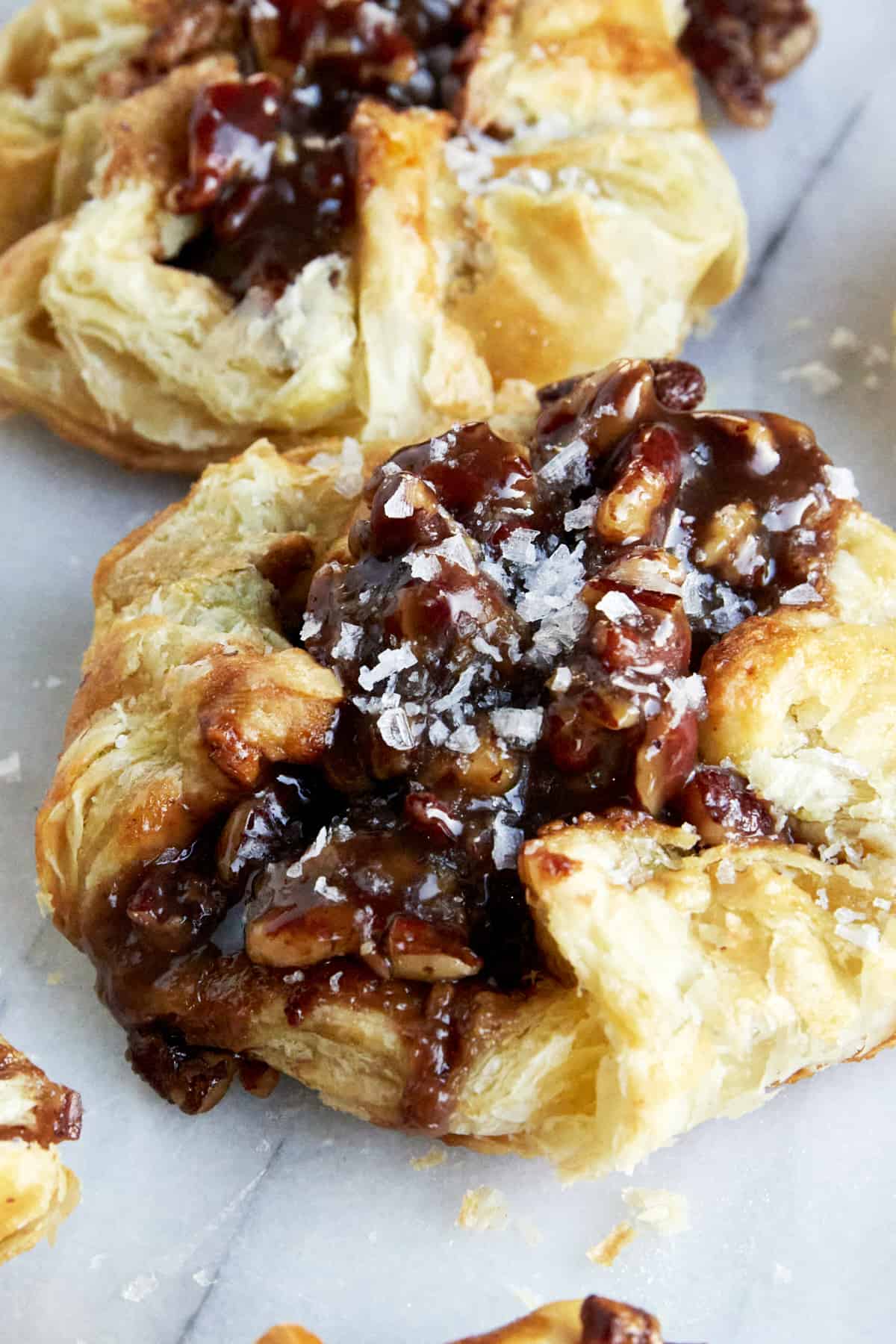 A baked pecan pie puff pastry bite topped with flakey salt. 