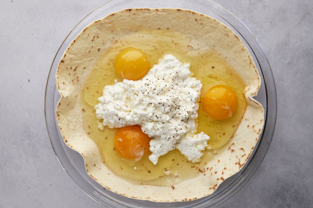 Three eggs and cottage cheese over a large tortilla in a round dish. 