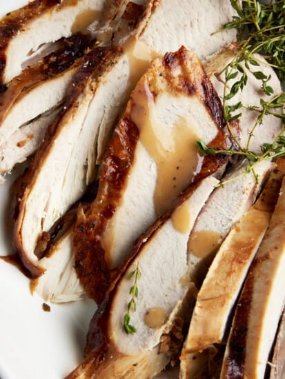 Slices of baked turkey drizzled with turkey gravy.