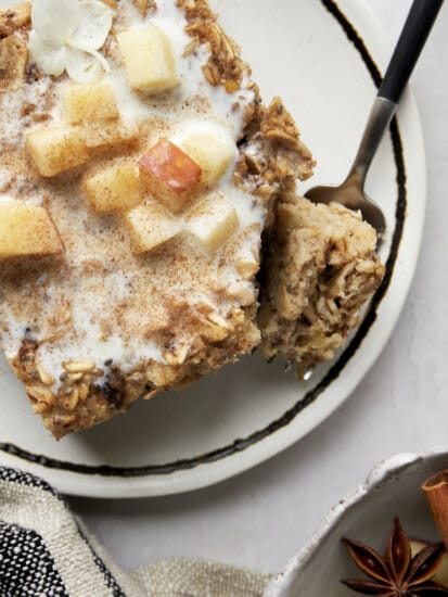 A serving of baked apple oatmeal on a plate with a fork holding a bite.