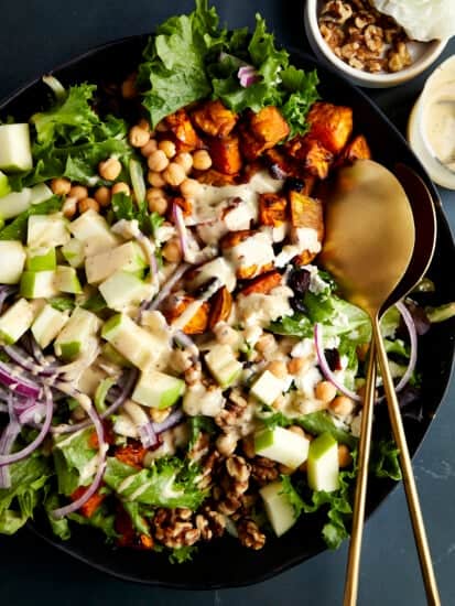 A bowl of sweet potato salad with chickpeas topped with tahini dressing.