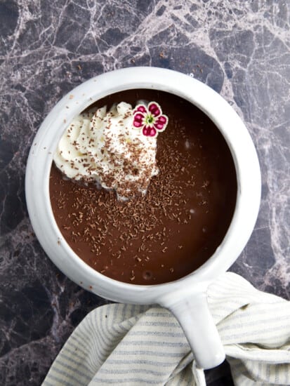 A mug of bone broth hot chocolate topped with whipped cream and chocolate shavings.