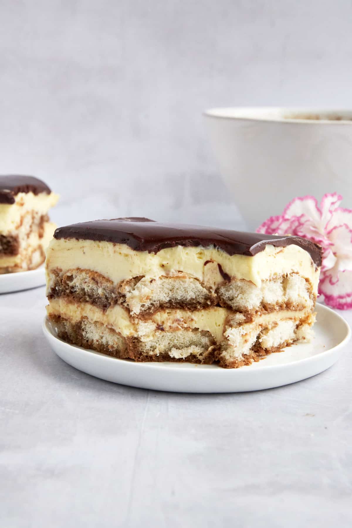 Tiramisu eclair cake on a plate with a bite missing from the corner. 