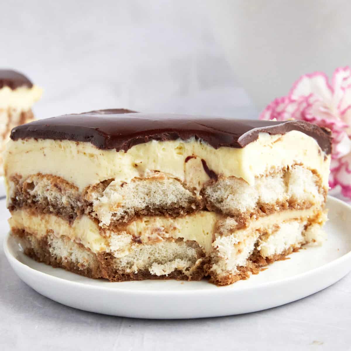 Tiramisu eclair cake on a plate missing a bite.