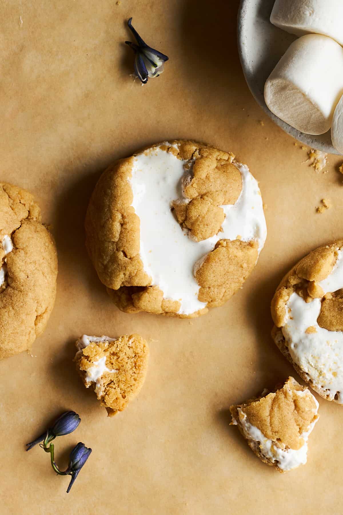Whole peanut butter fluff cookies next to pieces of cookie. 