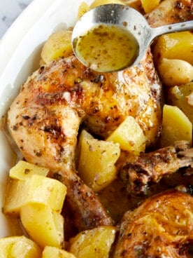 Baked lemon Greek chicken and potatoes in a baking dish.