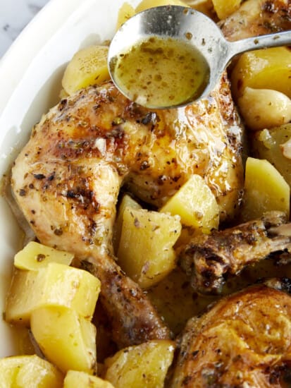 Baked lemon Greek chicken and potatoes in a baking dish.