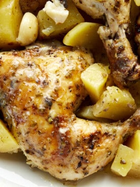 Greek chicken and potatoes in a baking dish.