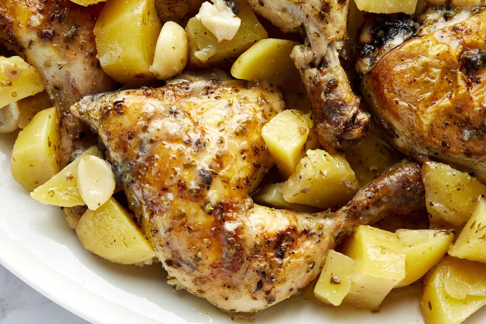 Greek chicken and potatoes in a baking dish.