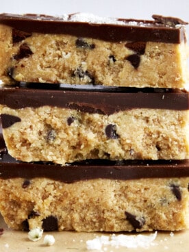 Three no-bake chocolate chip cookie dough bars on top of each other.