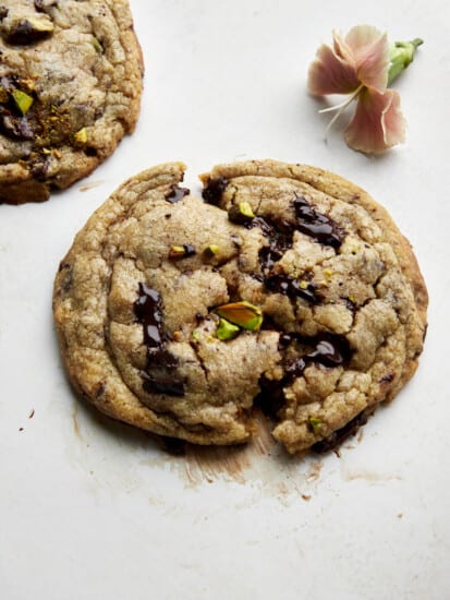 A brown butter pistachio chocolate chip cookie split in half.