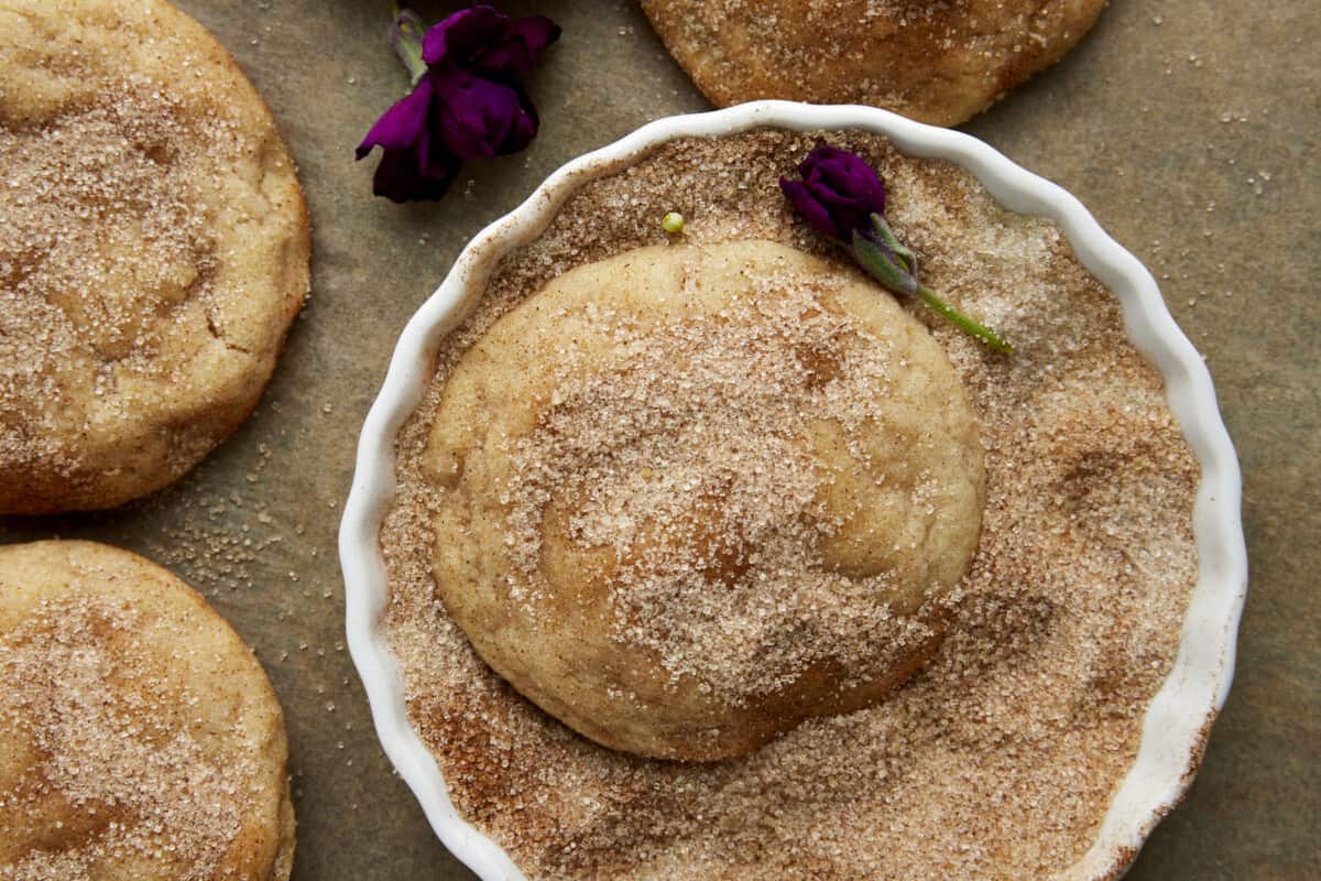 Snickerdoodle cookies being rolled in cinnamon sugar.