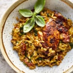 A bowl of one pot chicken and orzo topped with parsley.