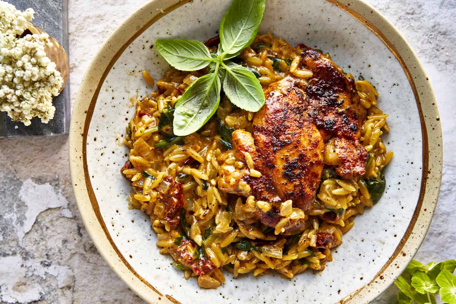 A bowl of one pot chicken and orzo topped with parsley.