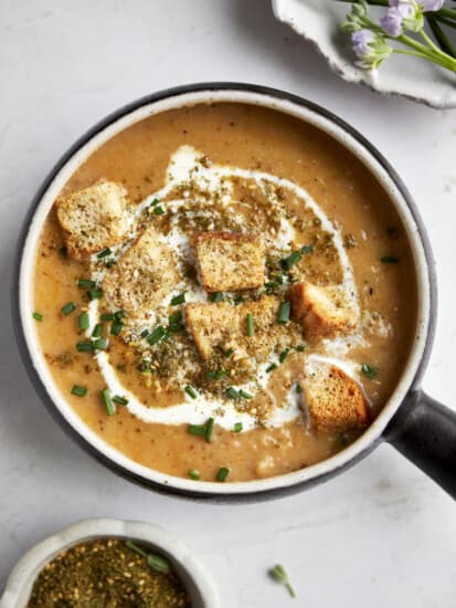 A bowl of roasted cauliflower soup topped with heavy cream, croutons, and za'atar.