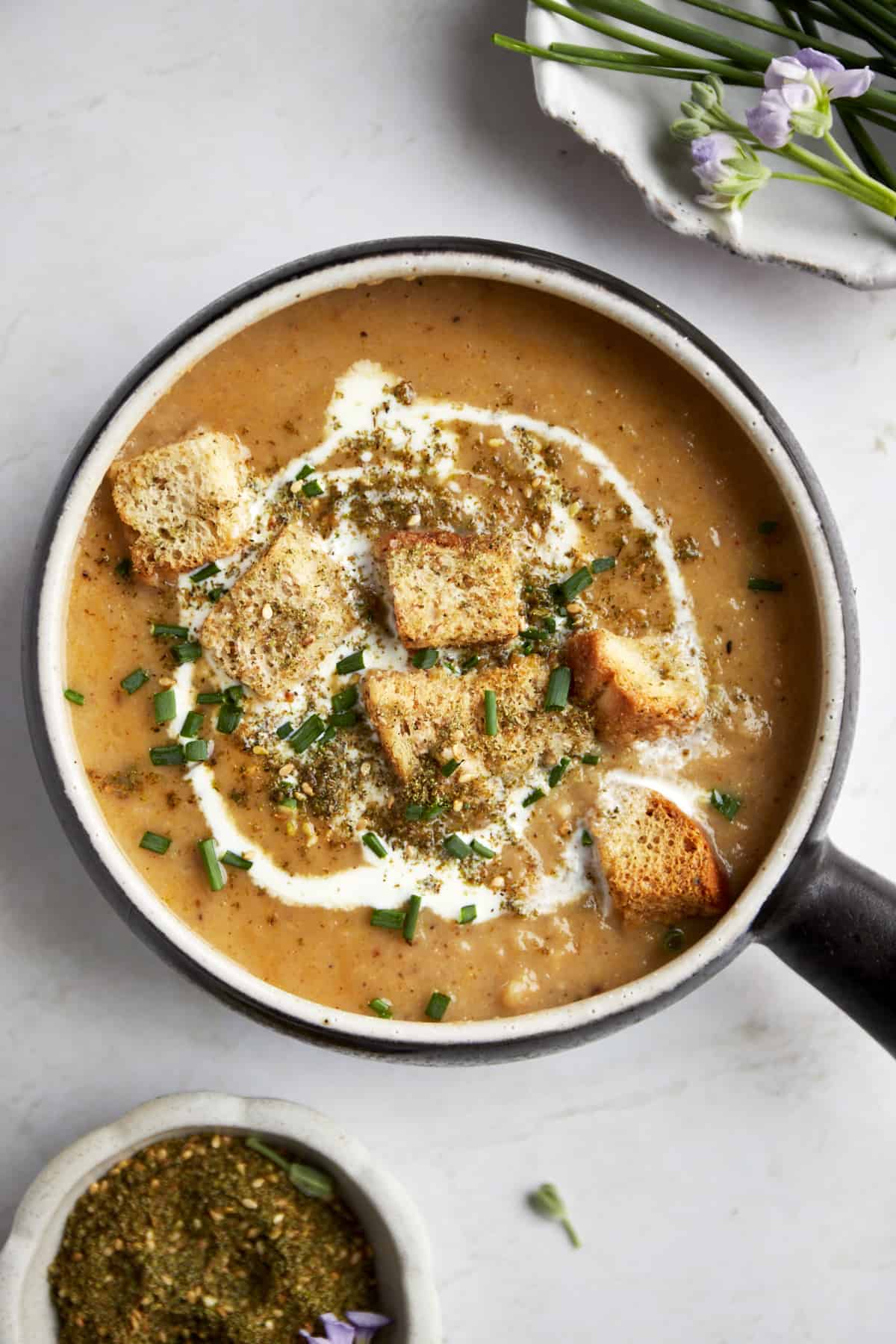 A bowl of roasted cauliflower soup topped with heavy cream, croutons, and za'atar.