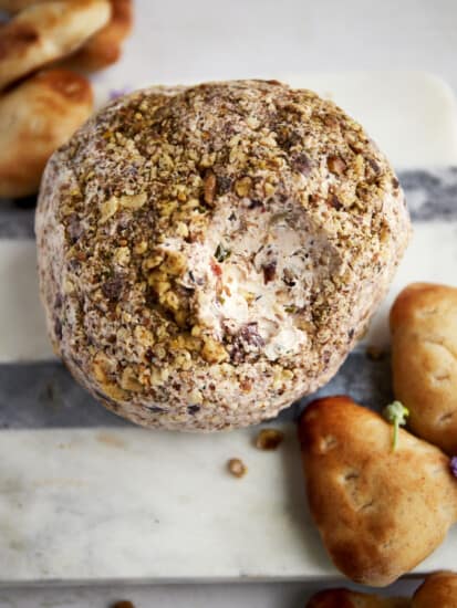 A Mediterranean cream cheese ball with a bite missing.
