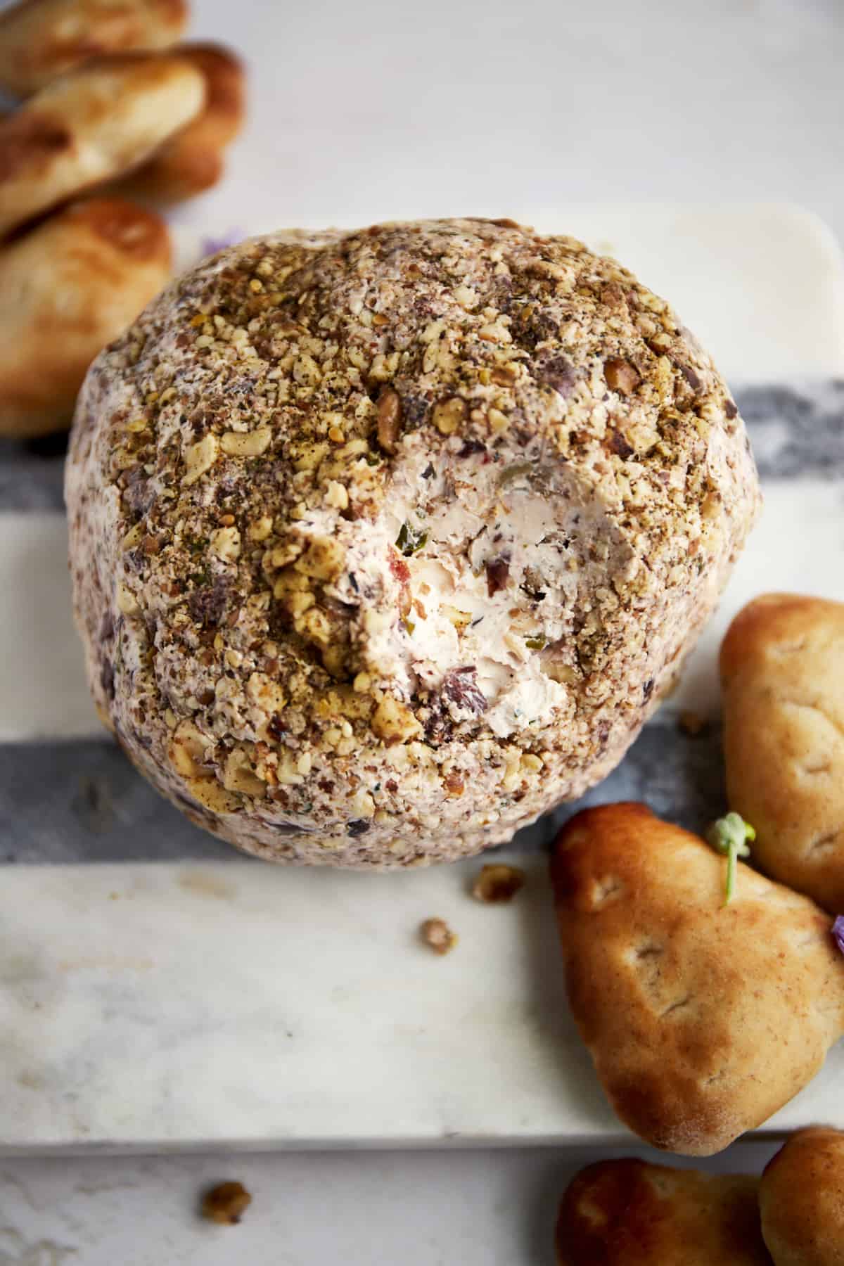 A Mediterranean cream cheese ball with a bite missing. 