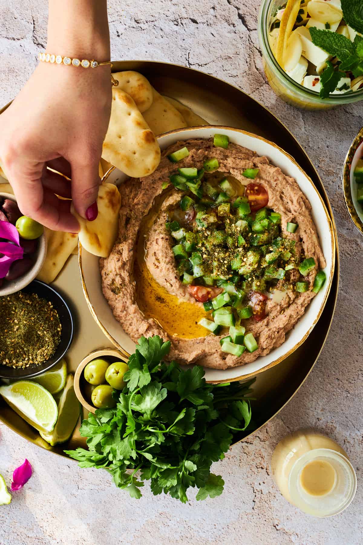 A hand dipping a pita chip into a bowl of ful medames.