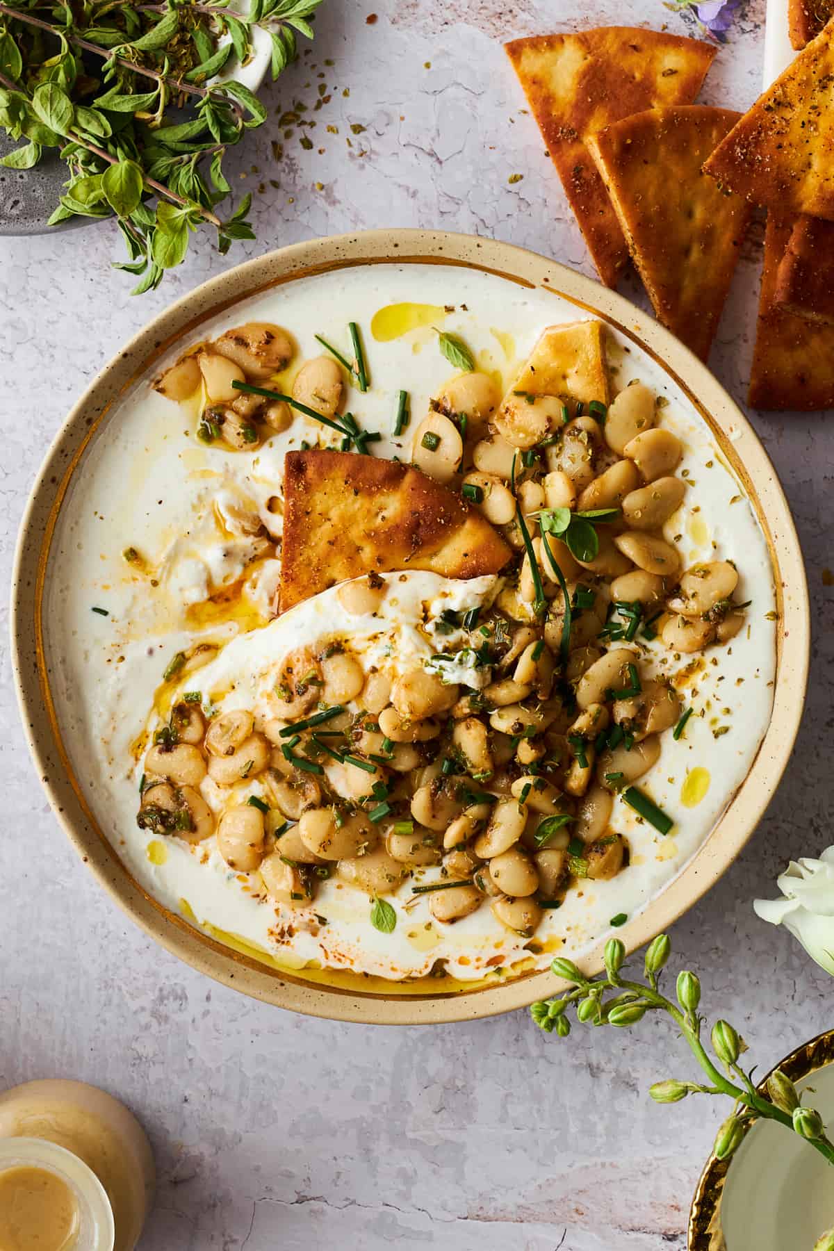 A bowl of marinated butter beans and cottage cheese with a pita chip dipped in. 