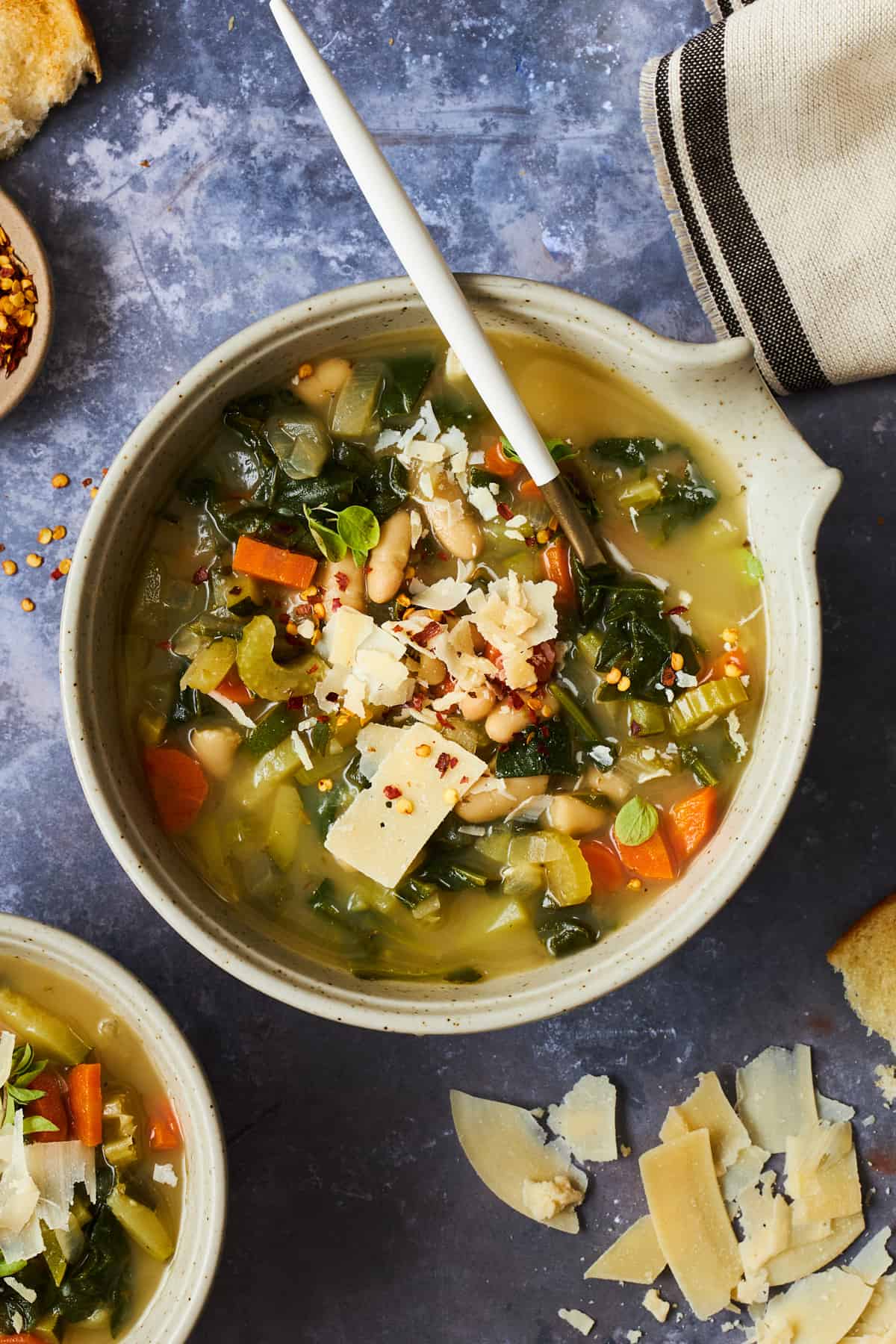 A bowl of cannellini bean soup with vegetables topped with parmesan. 