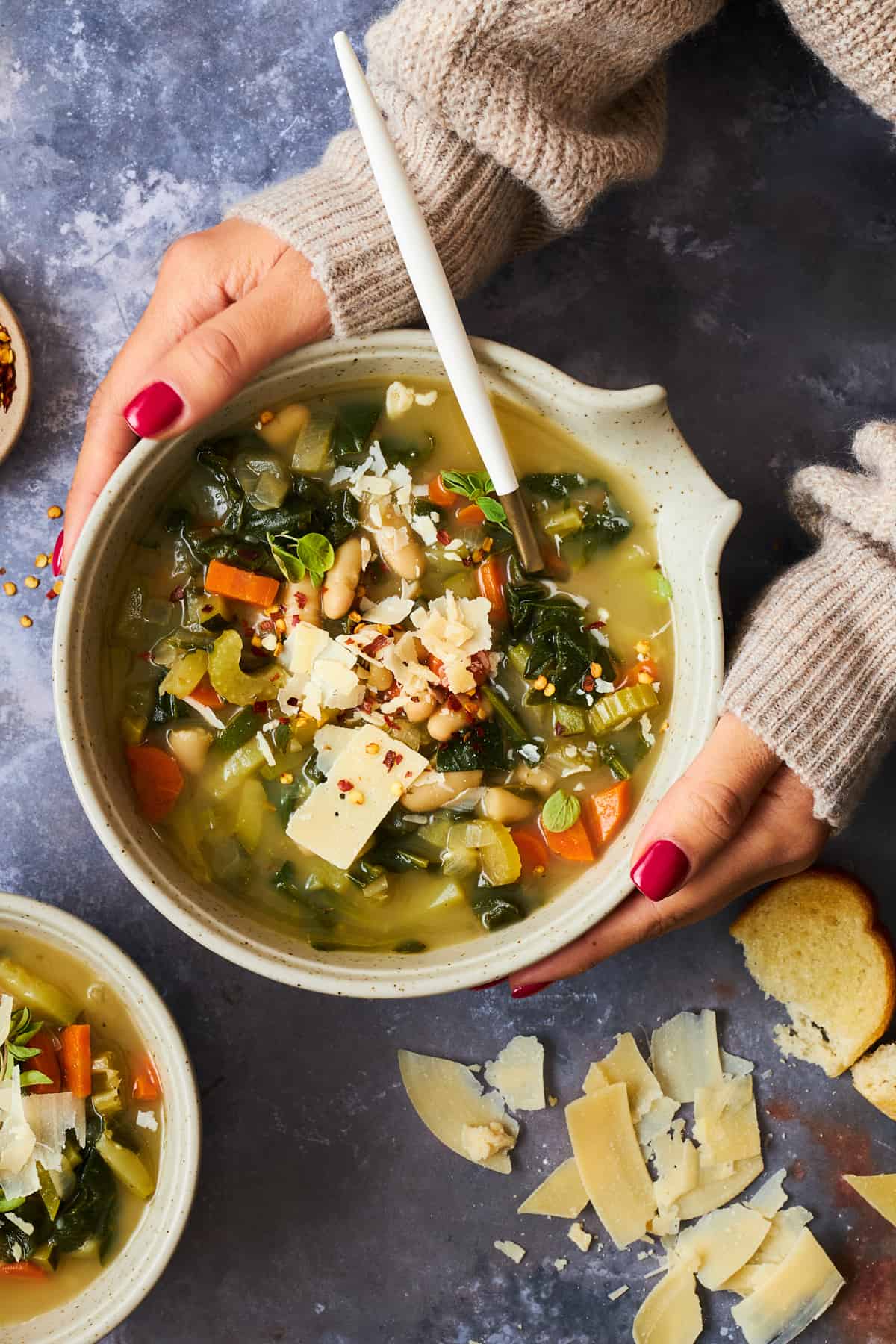 Two hands holding a bowl of cannellini bean soup. 