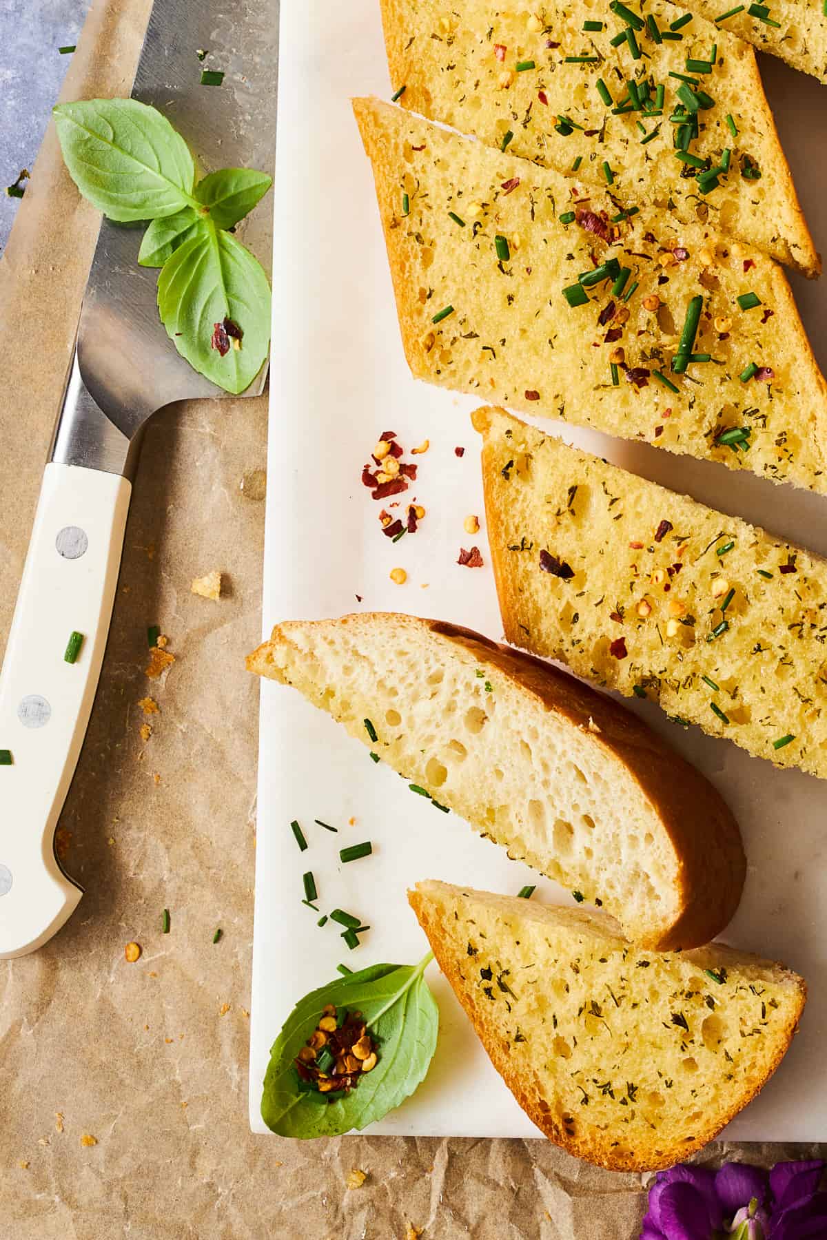 Slices of garlic bread on a cutting board next to a knife. 