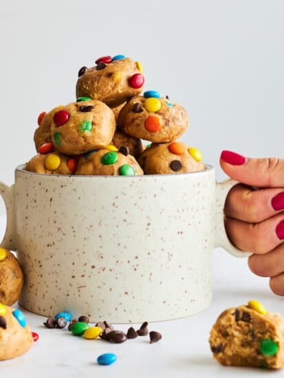 A hand holding a mug full of no-bake monster cookie energy bites.