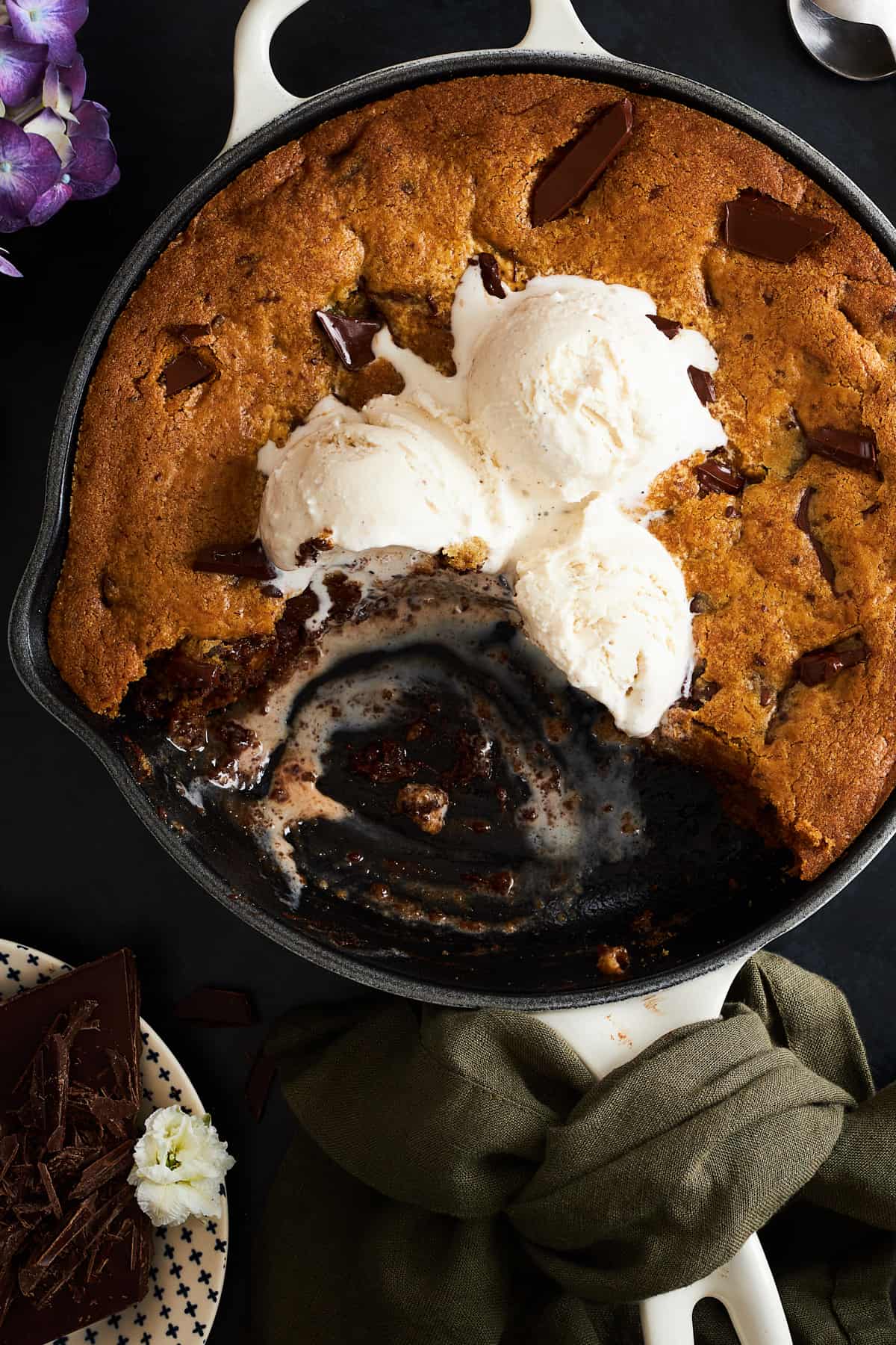 A chocolate chip skillet cookie topped with vanilla ice cream with bites missing. 