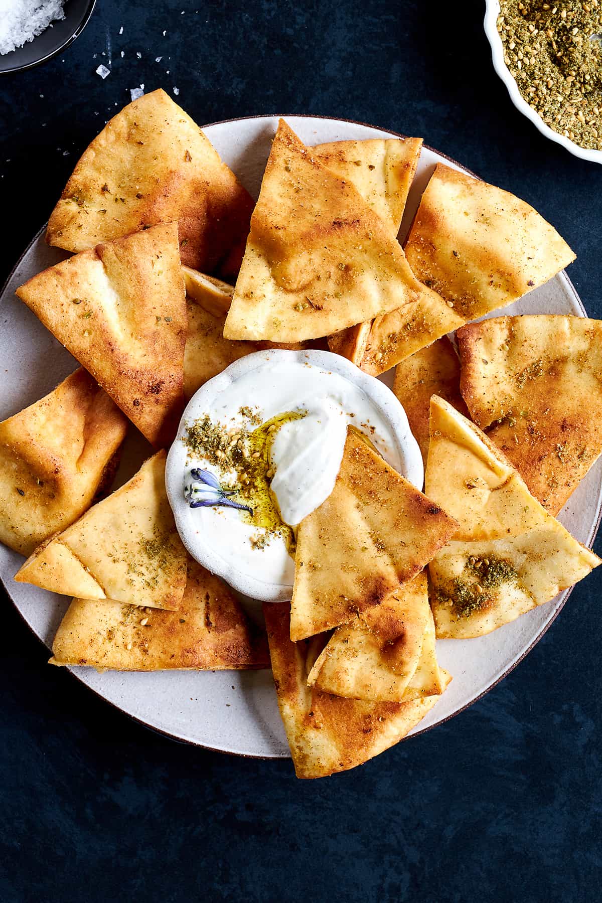 A platter of homemade pita chips with a creamy dip in the center. 