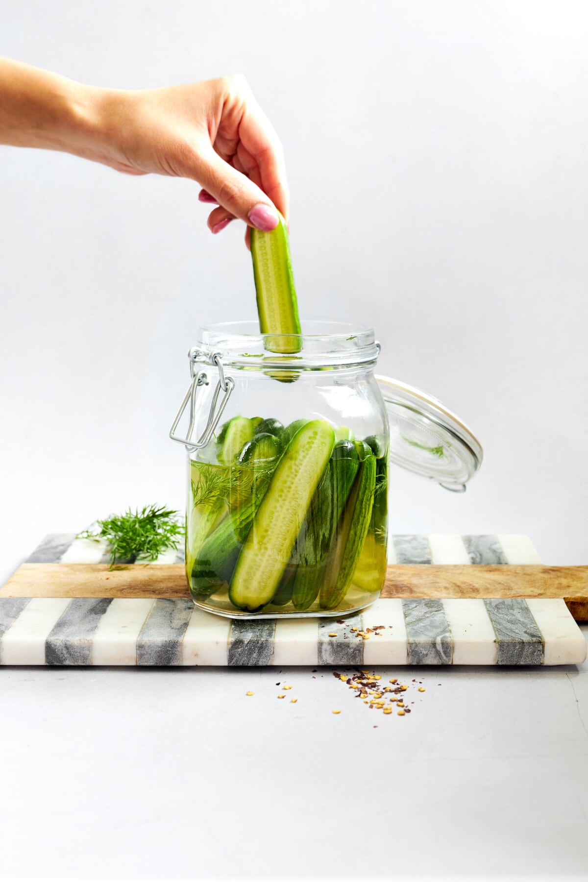 A marinated cucumber being pulled from a jar. 