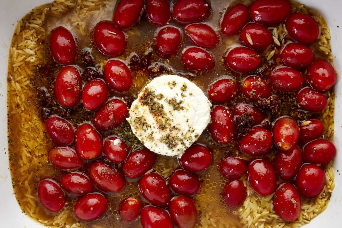 Tomatoes and Boursin cheese topped with olive oil and seasonings in a baking dish. 