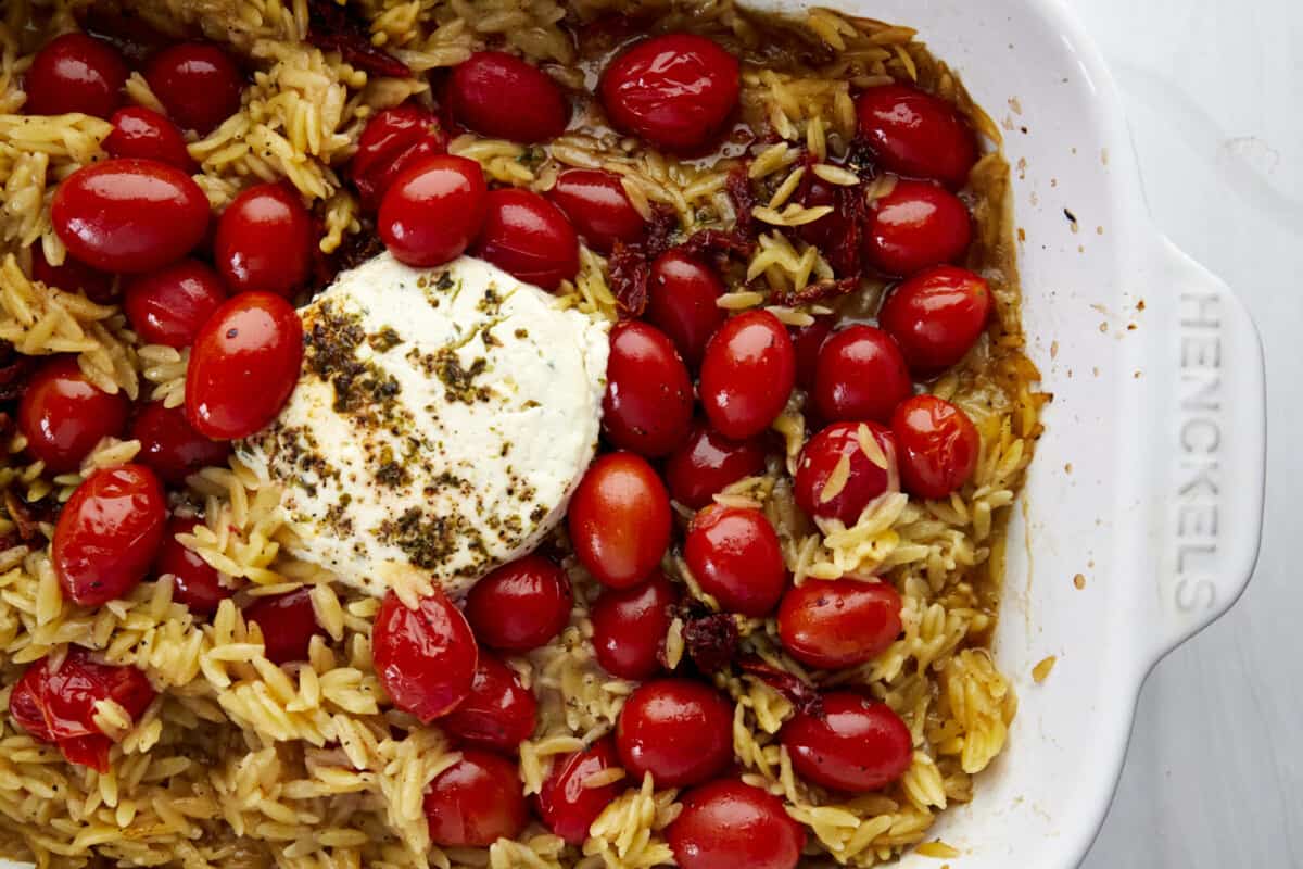 Uncooked pasta, tomatoes, Boursin cheese, and herbs in a baking dish. 