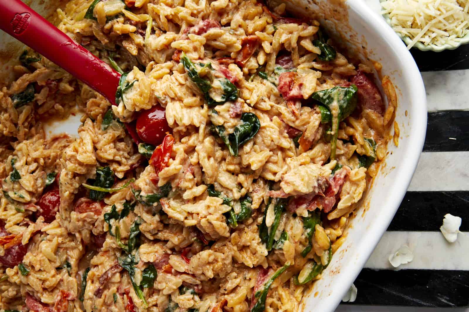 A spoon lifting a scoop of Boursin cheese pasta from a baking dish.