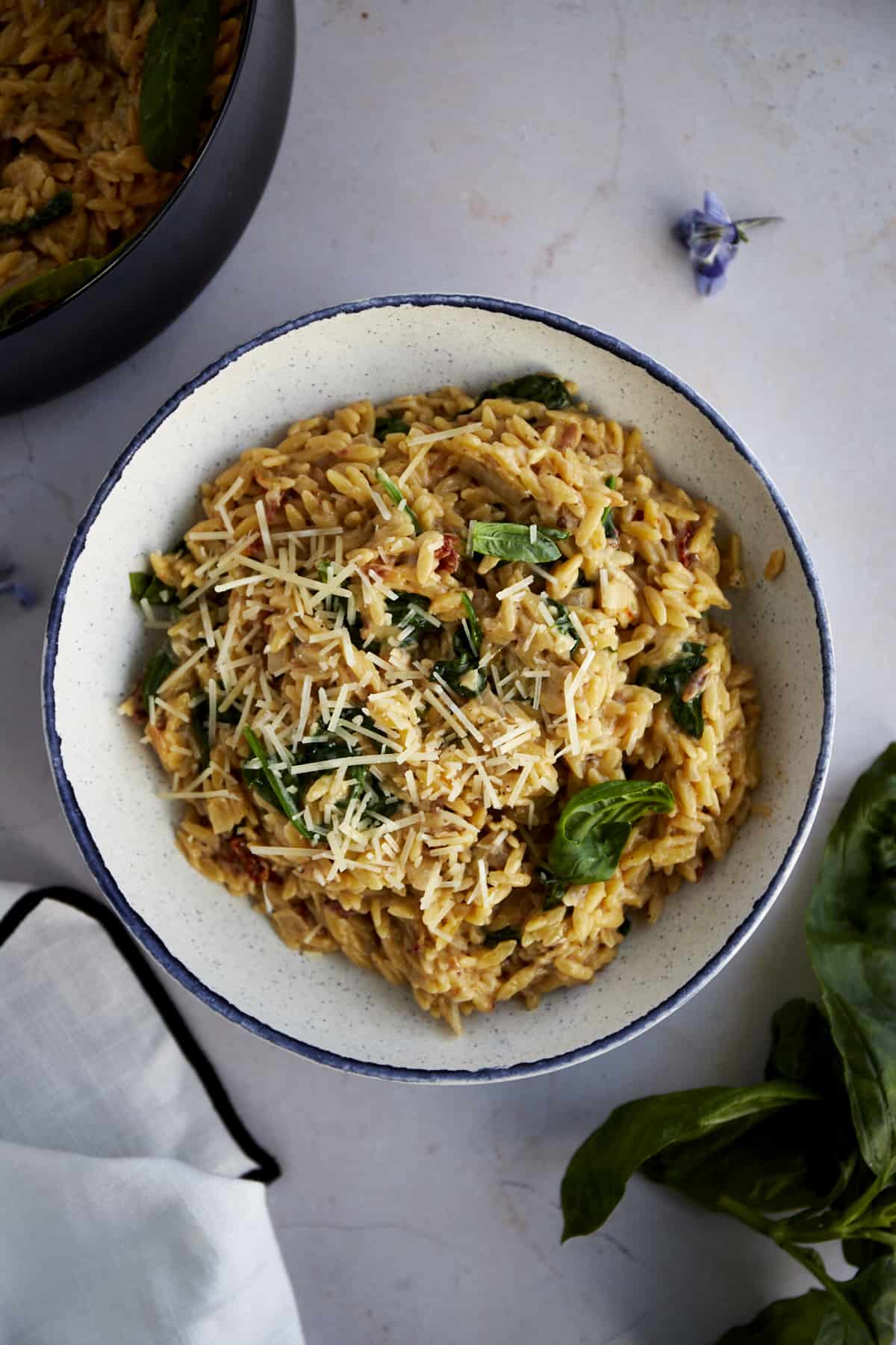 A bowl of creamy tuscan orzo pasta topped with parmesan. 