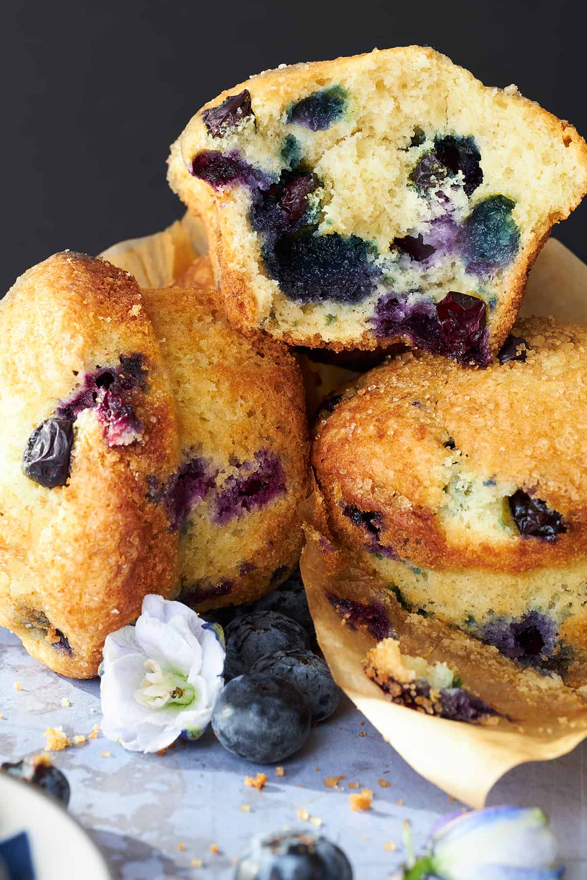 A pile of Starbucks blueberry muffins with one split in half exposing the center. 
