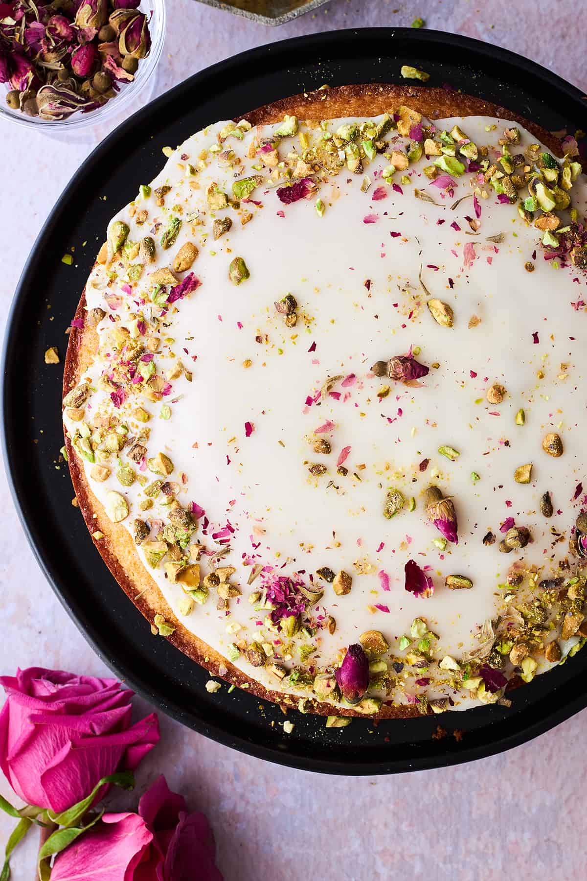A Persian love cake topped with orange glaze, rose petals, and pistachios. 
