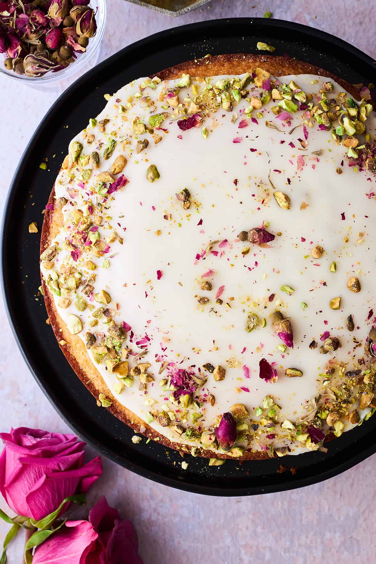 A Persian love cake topped with orange glaze, rose petals, and pistachios.