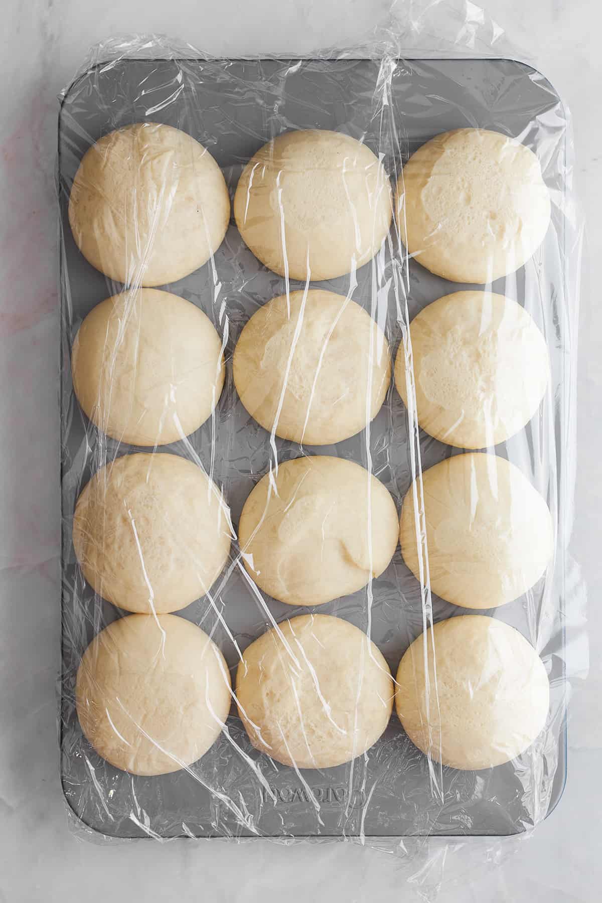 Risen bread rolls in a muffin tin. 