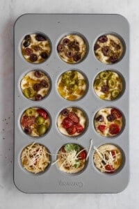 Unbaked focaccia muffins in a muffin pan.