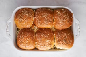 Unbaked ground beef sliders with cheese in a baking dish.