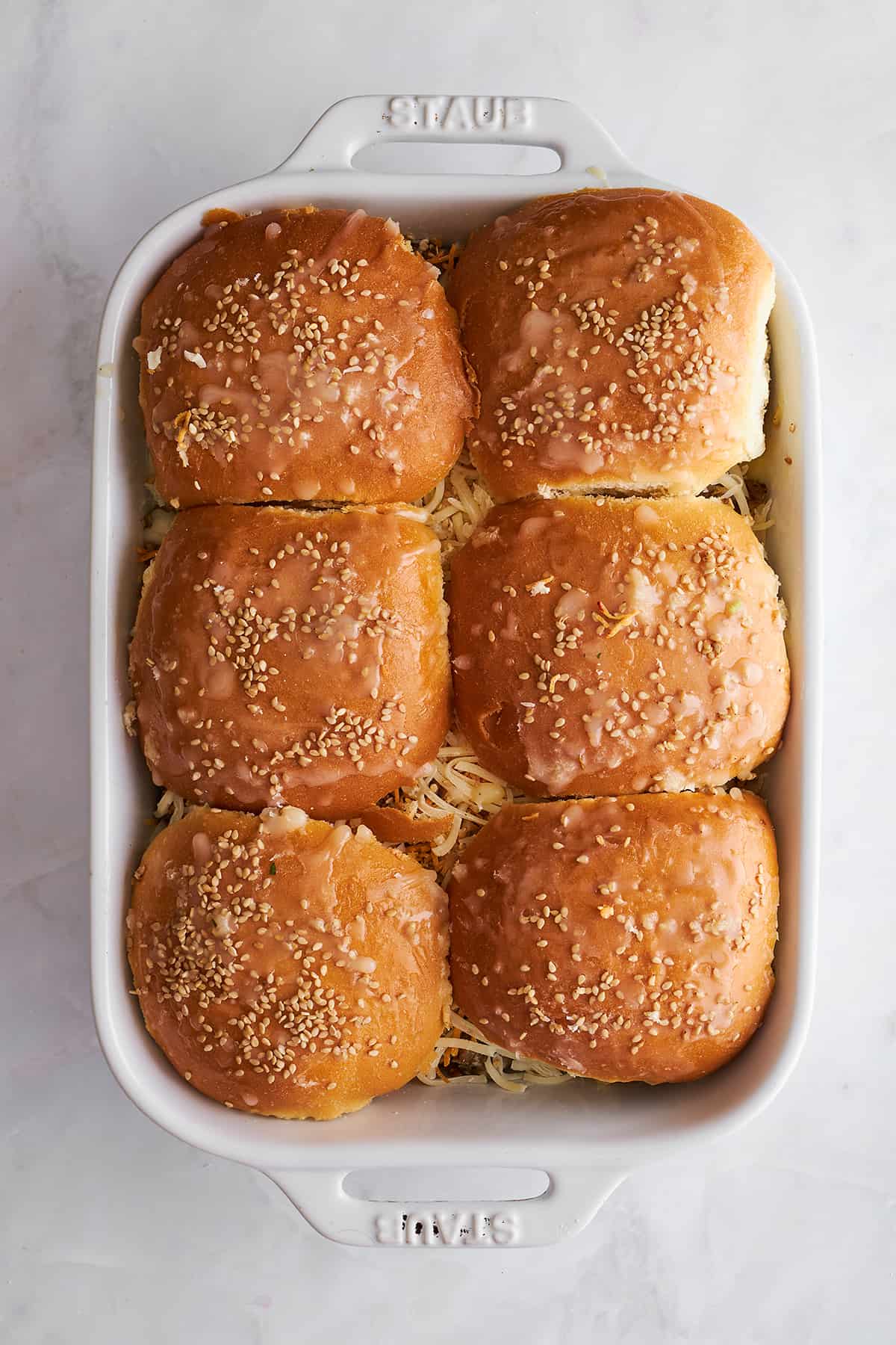 Unbaked ground beef sliders in a baking dish. 