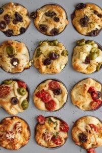 Baked focaccia muffins in a muffin pan.